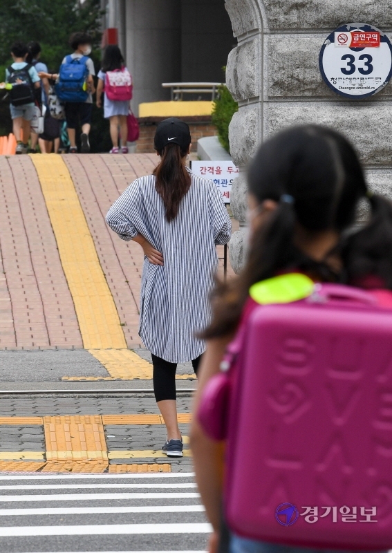 인천을 비롯한 수도권지역의 학교 밀집도 최소화 조치를 시작한 18일 오전 서구 초은 초등학교 교문에서 한 학부모가 개학 등교에 나선 자녀를 지켜보고 있다.이날 학교는 홀수학년에 홀수번호 학생들만 등교시켜 선제적인 1/4 밀집도 최소화 조치를 시행했다. 장용준기자