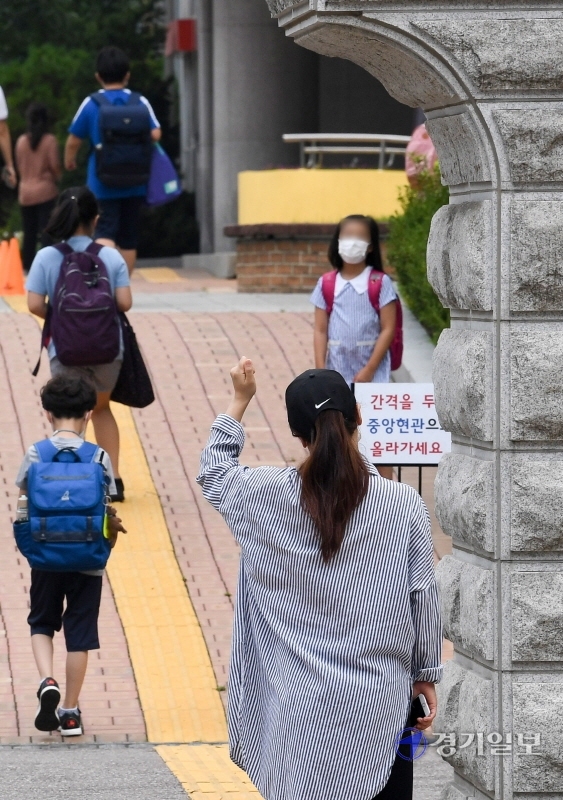 인천을 비롯한 수도권지역의 학교 밀집도 최소화 조치를 시작한 18일 오전 서구 초은 초등학교 교문에서 한 학부모가 개학 등교에 나선 자녀를 보며 응원하고 있다. 이날 학교는 홀수학년에 홀수번호 학생들만 등교시켜 선제적인 1/4 밀집도 최소화 조치를 시행했다. 장용준기자