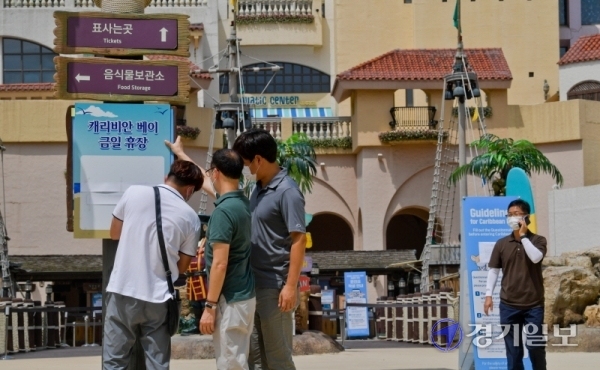 코로나19 확진자가 다녀간 것으로 알려져 19일 오전 임시휴장을 실시한 용인 에버랜드 캐리비안 베이에서 관계자들이 임시휴장 안내문을 붙이고 있다. 캐리비안 베이 관계자는 