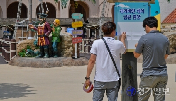 코로나19 확진자가 다녀간 것으로 알려져 19일 오전 임시휴장을 실시한 용인 에버랜드 캐리비안 베이에서 관계자들이 임시휴장 안내문을 붙이고 있다. 캐리비안 베이 관계자는 