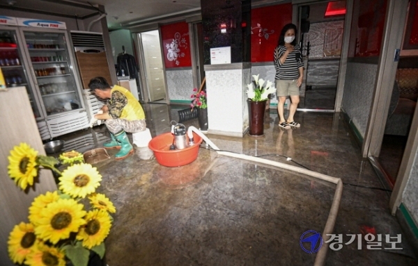 15일 오전 5시 30분께 성남종합운동장 사거리 일대가 지하 상수도관 파열로 물바다로 변한 가운데 침수 피해를 입은 한 상점에서 직원들이 배수 및 복구작업을 하고 있다. 이 사고로 오전 한때 차량 운행이 전면 통제되고 주택과 건물 등 1천여 세대의 수돗물 공급이 중단됐다. 조주현기자