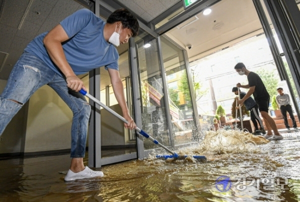 15일 오전 5시 30분께 성남종합운동장 사거리 일대가 지하 상수도관 파열로 물바다로 변한 가운데 침수 피해를 입은 한 상점에서 직원들이 배수 및 복구작업을 하고 있다. 이 사고로 오전 한때 차량 운행이 전면 통제되고 주택과 건물 등 1천여 세대의 수돗물 공급이 중단됐다. 조주현기자