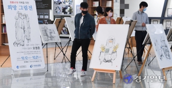 12일 오전 인천시청 중앙홀에서 공무원들이 오영준 길병원 간호사의 '코로나19 극복을 위한 희망 그림전'을 관람하고 있다. 전시작품에는 코로나19 발병초기에 길병원 음압실 병동에서 근무를 하며 스트레스와 애환을 겪는 오간호사의 동료들 모습이 사실적으로 담겨 있다. 장용준기자