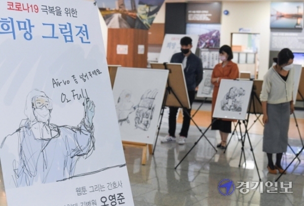 12일 오전 인천시청 중앙홀에서 공무원들이 오영준 길병원 간호사의 '코로나19 극복을 위한 희망 그림전'을 관람하고 있다. 전시작품에는 코로나19 발병초기에 길병원 음압실 병동에서 근무를 하며 스트레스와 애환을 겪는 오간호사의 동료들 모습이 사실적으로 담겨 있다. 장용준기자