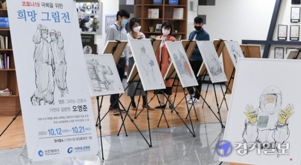 12일 오전 인천시청 중앙홀에서 공무원들이 오영준 길병원 간호사의 '코로나19 극복을 위한 희망 그림전'을 관람하고 있다. 전시작품에는 코로나19 발병초기에 길병원 음압실 병동에서 근무를 하며 스트레스와 애환을 겪는 오간호사의 동료들 모습이 사실적으로 담겨 있다. 장용준기자
