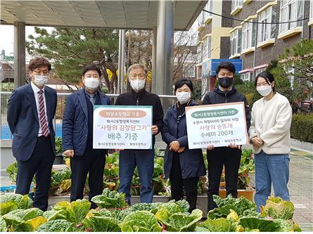 ▲ 화양초등학교 교직원과 팔달구청 화서2동 직원이 함께 상자텃밭 배추를 수확하고 상호 물품을 기증하고 있다