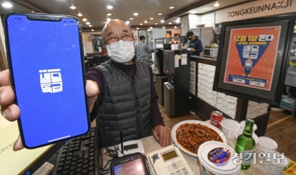 경기도 공공배달앱인 '배달특급'의 시범 서비스 시작을 하루 앞둔 30일 오후 파주시 문산읍 낙지요리전문점인 통큰낙지에서 상인 박찬범씨(74)가 배달특급 앱을 들어보이고 있다. 박씨는 