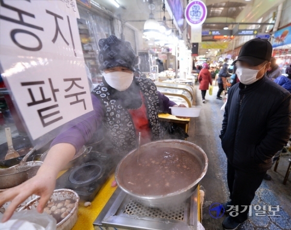 밤의 길이가 가장 길다는 동지(冬至)인 21일  인천 부평깡시장에서 시민들이 팥죽을 사가고 있다. 10년째 팥죽을 팔고 있다는 가게 주인은 