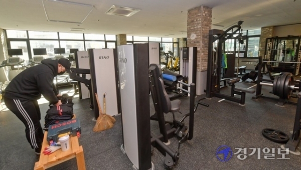 8일부터 코로나19 확산으로 영업금지 조치를 내렸던 모든 실내체육시설에 대해 동시간대 사용 인원을 9명으로 제한하는 조건으로 운영을 허용하기로 했다. 다만 이용 대상은 아동·청소년으로 제한돼 실효성이 지적되고 있다. 8일 오후 수원시 우만동의 한 헬스장에서 관계자가 매장을 정리하고 있다. 윤원규 기자