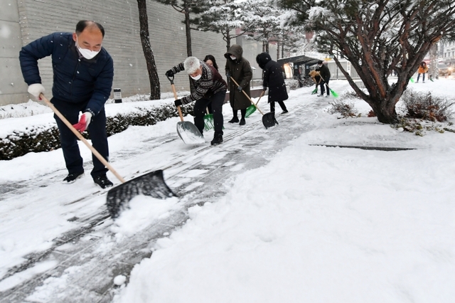 ▲ 12일 오후 수원시 행궁동 일대에서 공직자들이 제설작업에 투입돼 인도에 쌓인 눈을 치우고 있다.