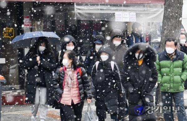 12일 오후 인천 미추홀구 경인전철 주안역 앞에서 시민들이 갑작스레 쏟아지는 눈을 맞으며 발걸음을 재촉하고 있다. 장용준기자