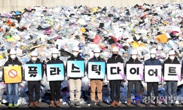 19일 오전 수원시자원순환센터 플라스틱 야외적치장에서 수원도시공사 임직원들이 '플라스틱 다이어트 함께 해요' 문구가 새겨진 피켓을 들고 '탈 플라스틱 캠페인'을 하고 있다.장용준기자