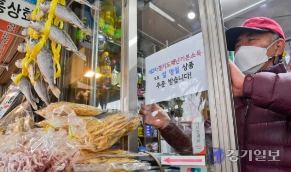 제2차 경기도 재난기본소득 온라인 신청이 시작된 1일 오후 수원시 팔달구 영동시장에서 상인 안경성씨가 재난기본소득으로 설 선물 주문을 받는다는 안내문을 붙이고 있다.  윤원규기자