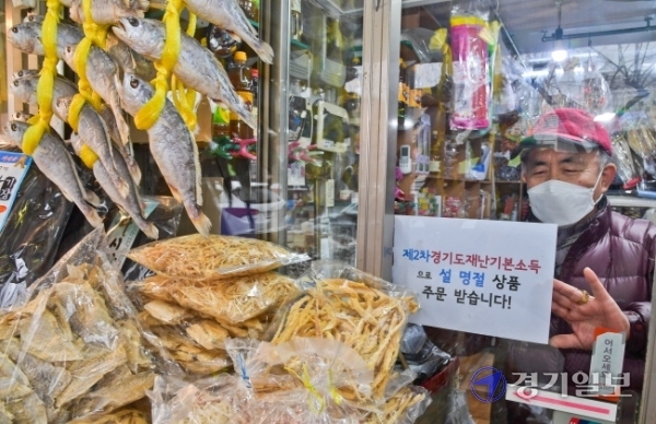 제2차 경기도 재난기본소득 온라인 신청이 시작된 1일 오후 수원시 팔달구 영동시장에서 상인 안경성씨가 재난기본소득으로 설 선물 주문을 받는다는 안내문을 붙이고 있다.  윤원규기자