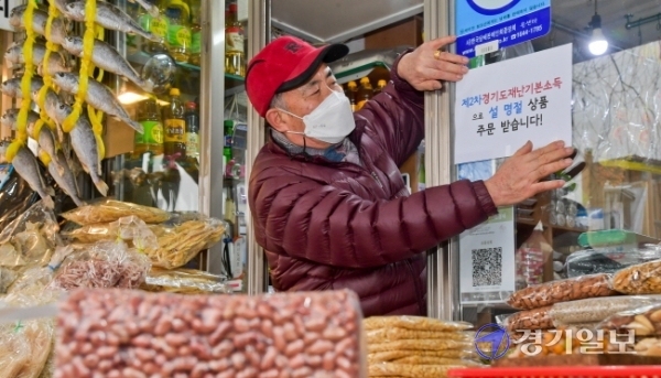 제2차 경기도 재난기본소득 온라인 신청이 시작된 1일 오후 수원시 팔달구 영동시장에서 상인 안경성씨가 재난기본소득으로 설 선물 주문을 받는다는 안내문을 붙이고 있다.  윤원규기자