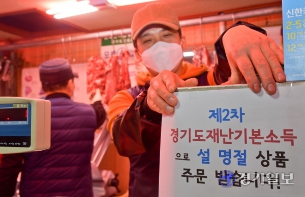 제2차 경기도 재난기본소득 온라인 신청이 시작된 1일 오후 수원시 팔달구 영동시장에서 상인 안경성씨가 재난기본소득으로 설 선물 주문을 받는다는 안내문을 붙이고 있다.  윤원규기자