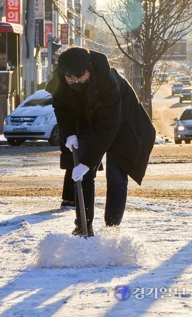 수원 7.3cm 등 밤사이 많은 눈이 내린 4일 오전 수원시 권선구 권선동 농수산시장 사거리에서 공무원들이 시민들을 위해 제설작업을 하고 있다. 윤원규기자