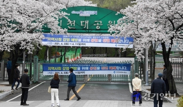 휴일인 4일 벚꽃이 만개한 인천대공원을 찾은 나들이객들이 아쉬운듯 코로나 19 예방을 위한 전면 폐쇄 현수막이 내걸린 후문 너머로 사진을 찍고 있다. 인천시는 시민들의 안전을 위해 벚꽃 개화기인 지난 3일부터 오는 11일까지 인천대공원과 월미공원, 자유공원, 수봉공원을 일시 폐쇄했다. 장용준기자