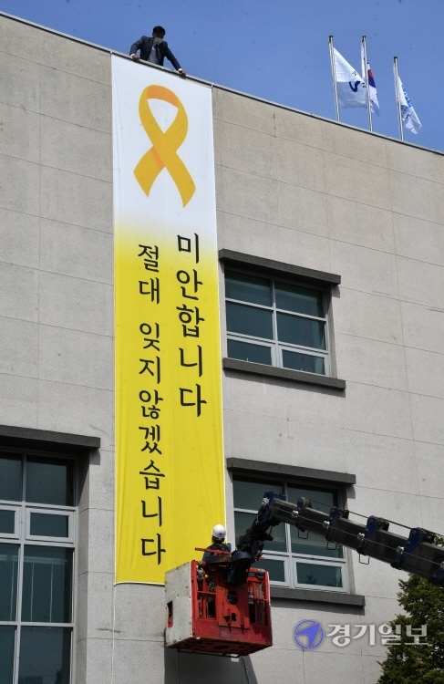 세월호 참사 7주기를 하루 앞둔 15일 오전 한국자유총연맹 수원시지회 건물 외벽에 세월호 희생자를 추모하는 대형 현수막이 설치되고 있다. 김주형 연맹 수원지회장은 
