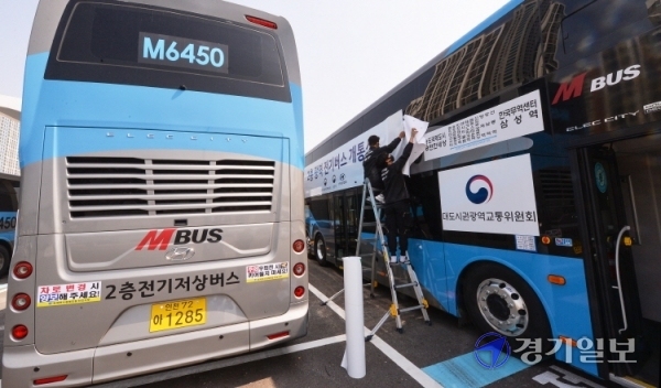 21일 오전 인천 연수구 송도국제도시내 M6450 버스차고지에서 관계자들이 인천 송도국제도시와 서울 강남을 오가는 광역노선에 새롭게 투입할 2층 전기버스에 개통식을 알리는 래핑작업을 하고 있다. 오는 26일부터 본격 운행할 예정인 이 버스에는 70명(1층 11석, 2층 59석)의 승객이 탑승해  환경부 인증 기준으로 1회 충전 시 최대 447km를 주행할 수 있다. 장용준기자