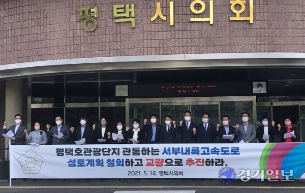 평택시의회 의원들이 지난 14일 평택시의회 앞에서 평택호관광단지를 관통하는 서부내륙고속도로로 모든 구간 교량화를 촉구하는 결의문을 낭독하고 있다. 정정화기자
