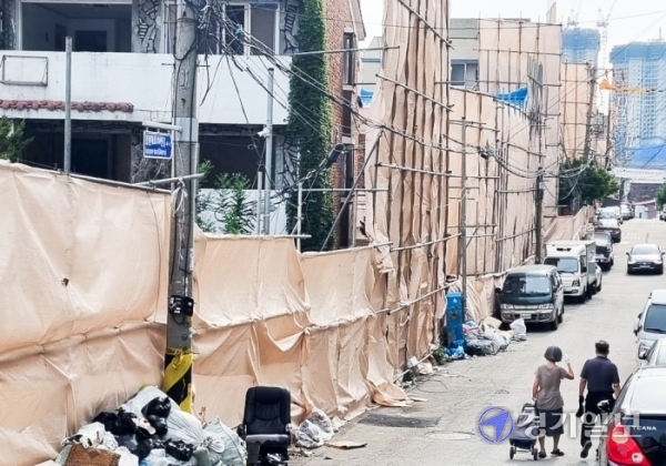 지난 12일 오후 인천 미추홀구 주안10구역 재개발 현장에서 철거가 한창인 가운데 부실한 천 가림막 옆을 주민들이 지나가고 있다. 강우진기자