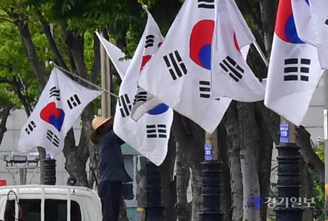 제헌절을 하루 앞둔 16일 오후 성남시 수정구 심곡동 일대에서 시 관계자가 도로변에 태극기를 게양하고 있다.조주현기자