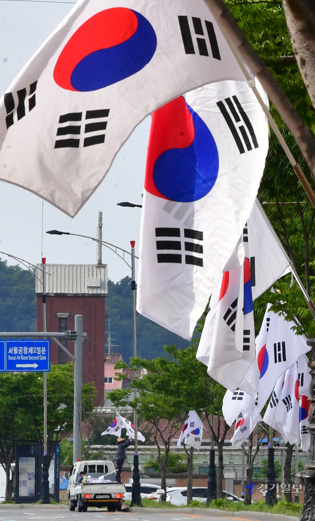 제헌절을 하루 앞둔 16일 오후 성남시 수정구 심곡동 일대에서 시 관계자가 도로변에 태극기를 게양하고 있다.조주현기자