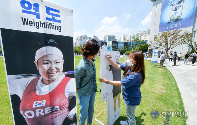 제32회 일본 도쿄올림픽 개막을 하루 앞둔 22일 오전 인천시청 애뜰광장에서 시민들이 인천 연고 선수들의 배너와 함께 세워진 입간판에 응원 메시지를 적고 있다. 장용준기자