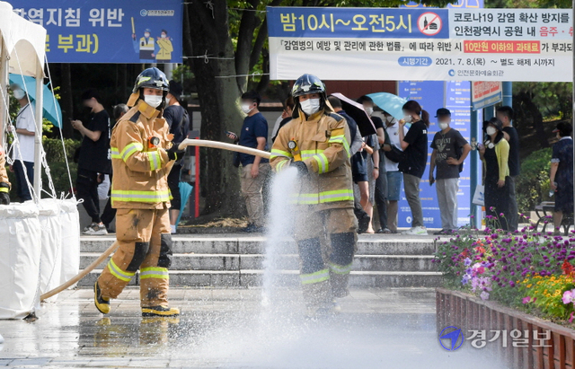 인천지역에 폭염경보가 내려진 26일 오후 남동구 중앙공원 코로나19 임시 선별검사소에서 남동소방서 소방관들이 검사소 주변 열기를 식히기 위해 물을 뿌리고 있다. 인천소방본부는 운영중인 10개의 임시선별검사소에 오전 10시와 오후 2시(폭염경보시 오후 4시)등 1일 2회 물을 뿌릴 계획이다. 장용준기자