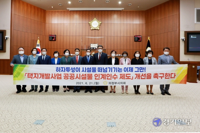의원들이 건의문을 채택한뒤 현수막을 앞에서  제도개선을 촉구하고 있다.