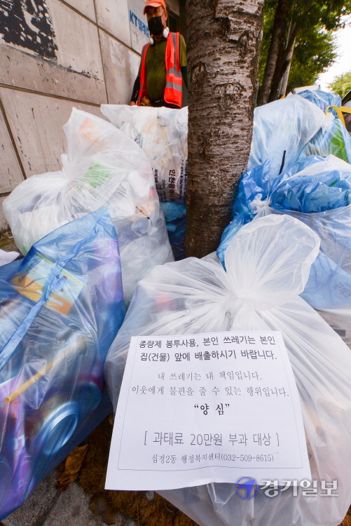 4일 오후 인천 부평구 경인국철 동암역 인근 거리에 쌓여있는 무단 투기 쓰레기 봉투에 '양심' 안내문이  붙어 있다. 장용준기자