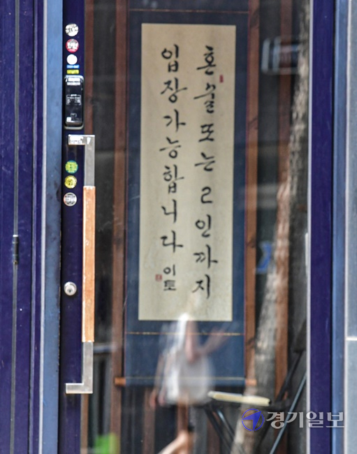 코로나19 확산세가 좀처럼 꺽이지 않자 정부가 현행 거리두기 단계를 2주 더 연장한다고 발표한 가운데 20일 오후 수원시내 한 주점에 '혼술 또는 2인까지 입장 가능합니다'라고 적힌 안내 족자가 걸려 있다. 정부는 거리두기 4단계인 지역에서 식당과 카페는 영업시간을 밤 10시에서 9시까지 단축하고, 저녁 6시 이후엔 백신 접종 완료자 2명을 포함해 총 4인까지 모일 수 있도록 했다. 조주현기자