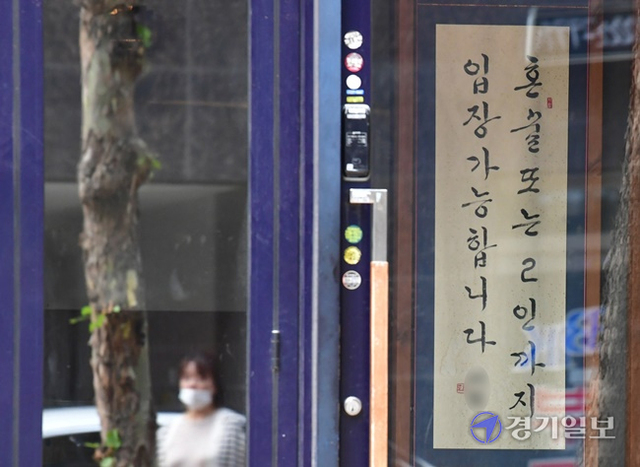 코로나19 확산세가 좀처럼 꺽이지 않자 정부가 현행 거리두기 단계를 2주 더 연장한다고 발표한 가운데 20일 오후 수원시내 한 주점에 '혼술 또는 2인까지 입장 가능합니다'라고 적힌 안내 족자가 걸려 있다. 정부는 거리두기 4단계인 지역에서 식당과 카페는 영업시간을 밤 10시에서 9시까지 단축하고, 저녁 6시 이후엔 백신 접종 완료자 2명을 포함해 총 4인까지 모일 수 있도록 했다. 조주현기자