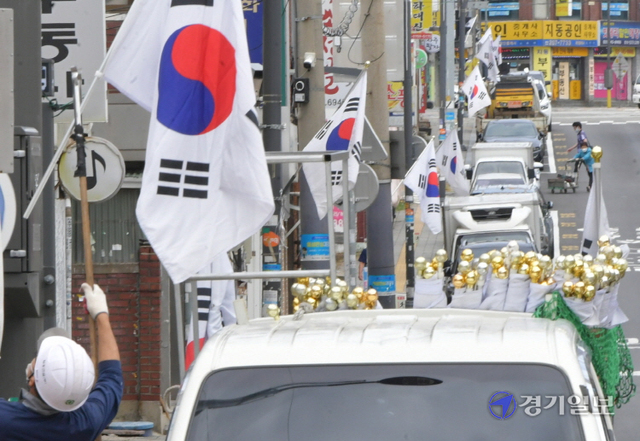 국군의 날과 개천절을 앞둔 28일 오전 수원시내 한 도로변에서 관계자가 태극기를 게양하고 있다. 조주현기자