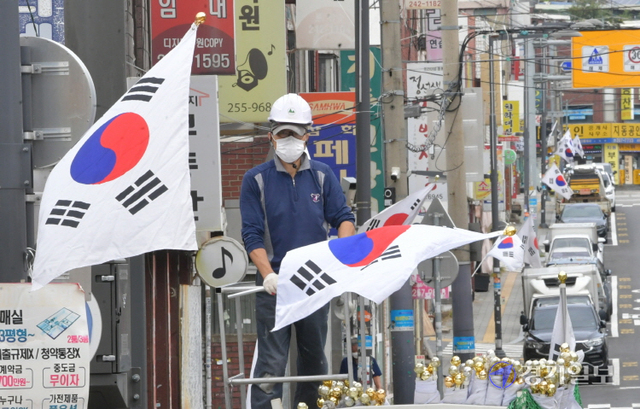 국군의 날과 개천절을 앞둔 28일 오전 수원시내 한 도로변에서 관계자가 태극기를 게양하고 있다. 조주현기자