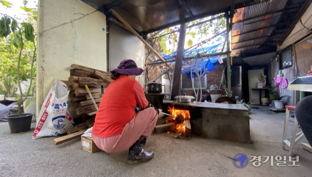 19일 아침 보일러가 돌지 않는 광명시 소하동의 판자촌에서 한 주민이 따뜻한 물을 쓰기 위해 아궁이에 불을 지피고 있다. 장희준기자