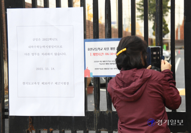 2022학년도 대학수학능력시험일인 18일 오전 수원시 효원고등학교 시험장 앞에서 한 학부모가 닫힌 철문 사이로 사진을 촬영하고 있다. 조주현기자
