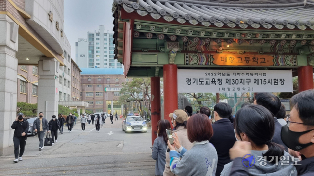 18일 대학수학능력시험이 치러진 수원 태장고등학교 정문에서 학부모들이 수험생들을 기다리고 있다. 박문기기자