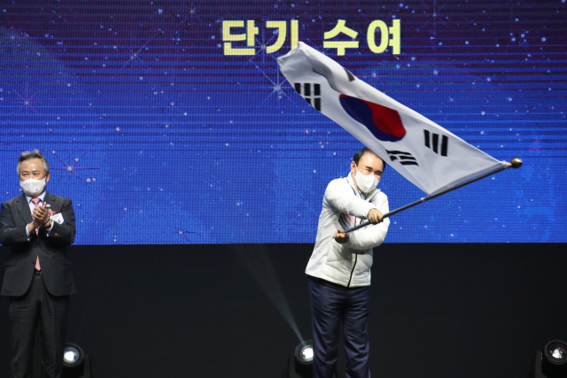 25일 서울 올림픽공원 올림픽홀에서 열린 2022 베이징 동계올림픽 선수단 결단식에서 윤홍근 선수단장이 단기를 받아 흔들고 있다. 왼쪽은 이기흥 대한체육회장.연합뉴스