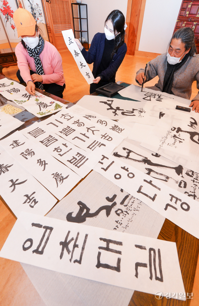 입춘(立春)을 하루 앞둔 3일 오후 '압화로 꾸미는 입춘방' 체험 행사가 열린 인천 계양구 인천농업기술센터에서 송연관 작가를 비롯한 농업기술센터 관계자들이 시민들에게 나눠 줄 입춘방을 쓰고 있다.인천농업기술센터는 코로나19 확산방지를 위해 90명의 시민들에게 6회에 걸쳐 입춘방과 압화 재료를 나눠준 뒤 각 가정에서 입춘방 체험 후기를 작성하는 것으로 마무리 했다. 장용준기자