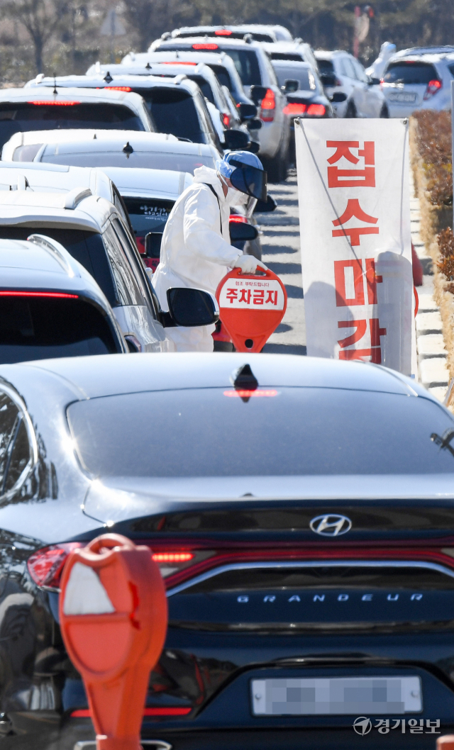 코로나19 변이 바이러스인 오미크론의 확산으로 인천지역에 사상 최다인 1만1천63명의 1일 신규 확진자가쏟아져 나온 23일 오전 10시 50분께 연수구 선학경기장 드라이브스루 임시선별검사소 입구에서 의료진이 밀려드는 검사객 차량행렬속에서 조기 접수마감 안내를 하고 있다. 장용준기자