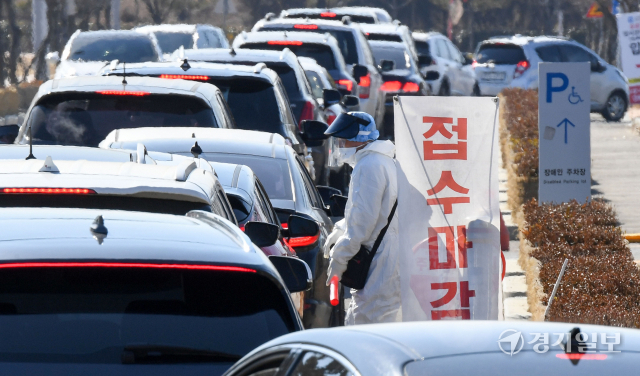 코로나19 변이 바이러스인 오미크론의 확산으로 인천지역에 사상 최다인 1만1천63명의 1일 신규 확진자가쏟아져 나온 23일 오전 10시 50분께 연수구 선학경기장 드라이브스루 임시선별검사소 입구에서 의료진이 밀려드는 검사객 차량행렬속에서 조기 접수마감 안내를 하고 있다. 장용준기자