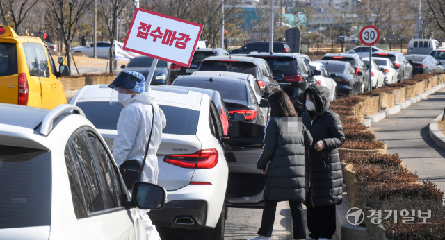 코로나19 변이 바이러스인 오미크론의 확산으로 인천지역에 사상 최다인 1만1천63명의 1일 신규 확진자가쏟아져 나온 23일 오전 10시 50분께 연수구 선학경기장 드라이브스루 임시선별검사소 입구에서 의료진이 밀려드는 검사객 차량행렬속에서 조기 접수마감 안내를 하고 있다. 장용준기자