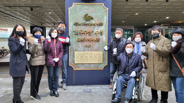 율천동 주민자치회가 지난해 제20회 전국주민자치 박람회 최우수상 수상 기념으로 현판을 세우고 기념촬영을 하고 있다.