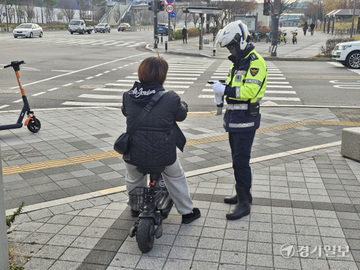 27일 오후 남양주시 별내동의 한 사거리에서 헬멧 없이 개인형 이동장치(PM)를 타던 B씨(30대)가 경찰관으로부터 범칙금 처분을 받고 있다. 김기현기자