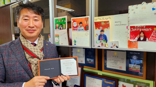 엄형원 대표가 20년 동안 월드비전을 통해 자신이 후원한 3명의 아이들 사진 앞에서 포즈를 취하고 있다. 김정규기자