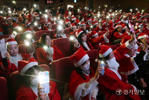 19일 오후 수원특례시청에서 열린 '제12회 수원 사랑의 산타' 행사에서 300여 명의 산타 자원봉사자 등이 휴대폰 불빛을 비추고 있다. 김시범기자