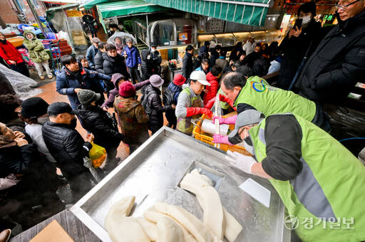 17일 오후 수원특례시 팔달구 못골종합시장에서 열린 '제11회 가래떡 나눔 행사'에서 시민들이 2백여미터의 가래떡을 뽑아 시장을 걸으며 새해 건강과 행운을 기원하고 있다. 윤원규기자