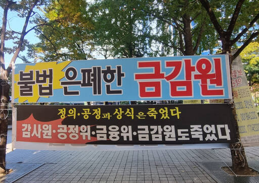 부동산 신탁사업자의 신탁계약서상 불공정 약관 불법 사용 문제를 지적하는 일부 투자자들은 공정거래위원회와 금융위원회 등 관련 기관들이 ‘불공정 약관 시정명령 등을 제대로 이행하지 않고 있다’며 반발하고 있다. 감사원은 국민감사청구에 따라 지난해 11월부터 공정위에 대한 감사를 벌이고 있다. 사진은 서울 여의도 금융감독위원회 앞 노상에 투자자들이 설치한 현수막. 국민감사청구인측 제공